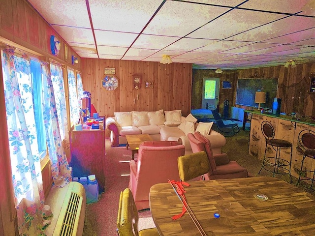 carpeted dining area with wood walls