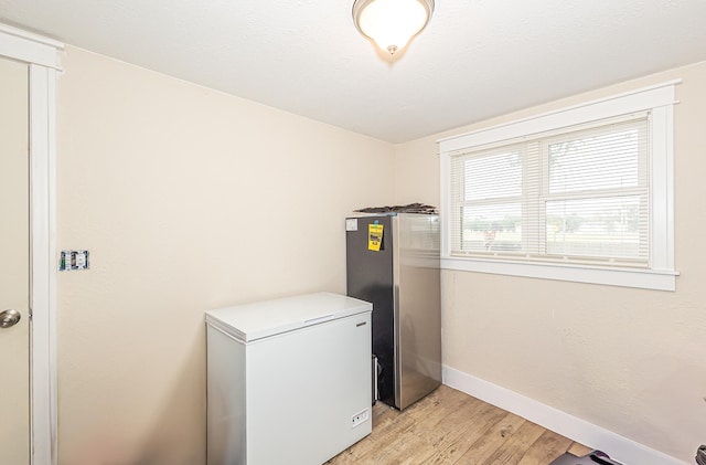 clothes washing area with light hardwood / wood-style flooring