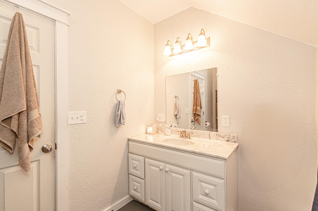 bathroom featuring vanity and lofted ceiling