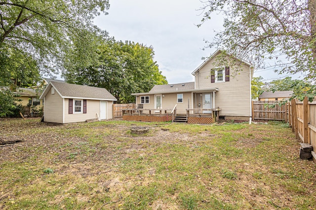 rear view of house with an outdoor structure, a deck, and a yard