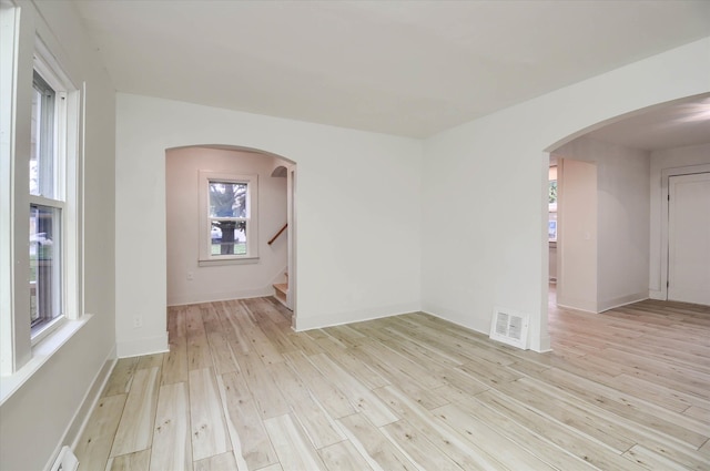 unfurnished room featuring a wealth of natural light, light hardwood / wood-style floors, and a baseboard radiator