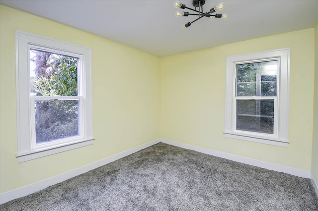 empty room featuring carpet flooring and an inviting chandelier