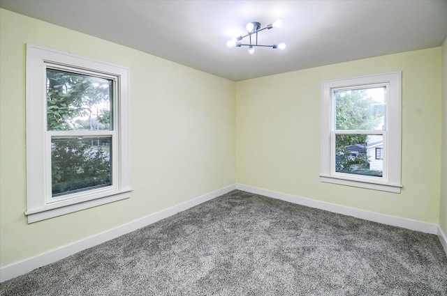 carpeted empty room with an inviting chandelier