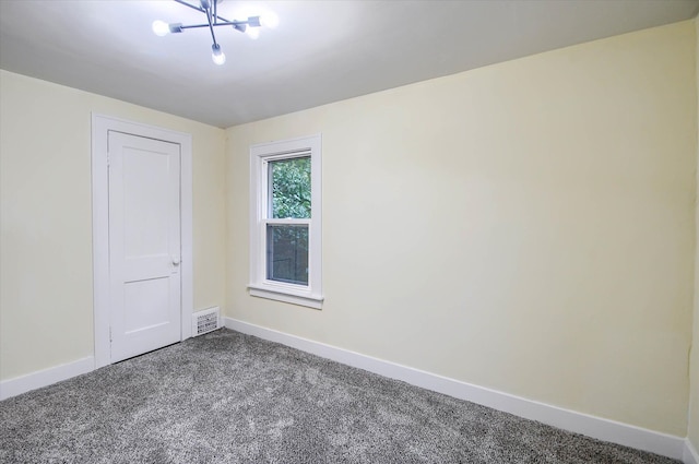 carpeted empty room with a chandelier