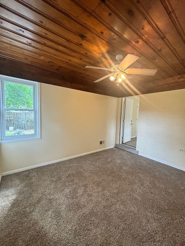 carpeted spare room with wood ceiling and brick wall