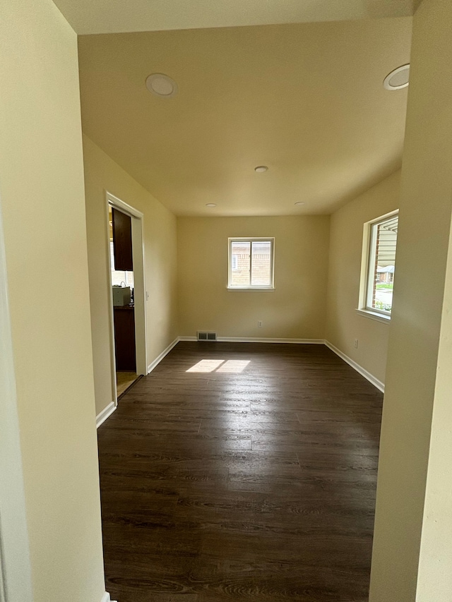 empty room featuring a wealth of natural light and dark hardwood / wood-style flooring