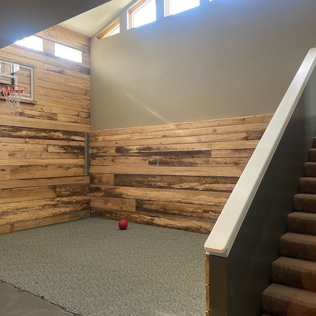 stairs featuring carpet floors, lofted ceiling, and wood walls