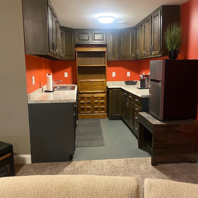 kitchen featuring dark brown cabinetry, stainless steel fridge, and sink