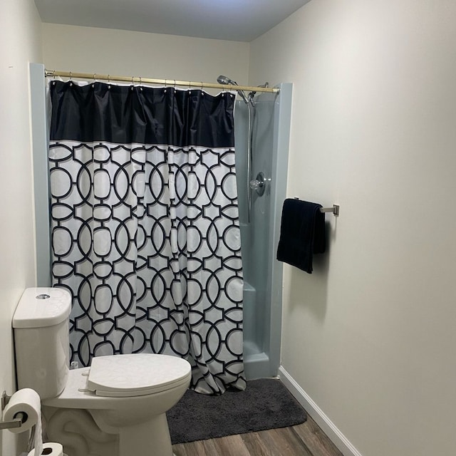 bathroom featuring hardwood / wood-style flooring, toilet, and walk in shower