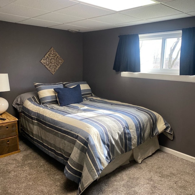 bedroom featuring a drop ceiling and carpet