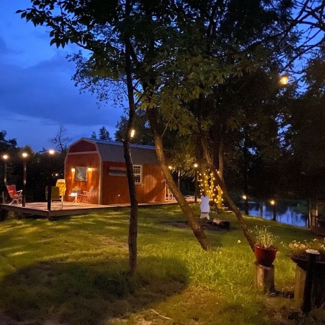 back of house featuring a deck with water view, a yard, and an outbuilding