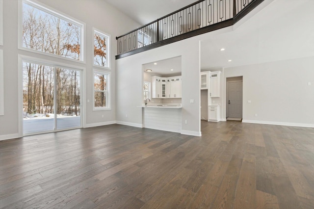 unfurnished living room featuring dark hardwood / wood-style floors and a towering ceiling