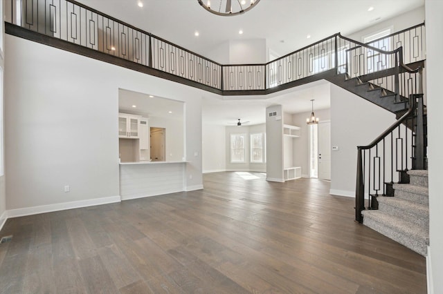 unfurnished living room featuring a high ceiling, dark hardwood / wood-style floors, and a notable chandelier