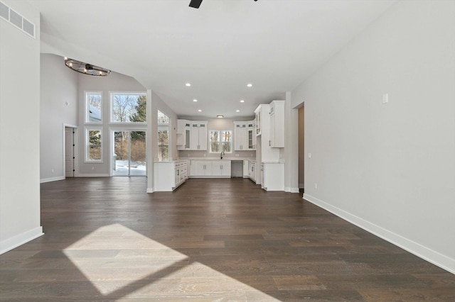 unfurnished living room featuring dark wood-type flooring, ceiling fan, vaulted ceiling, and sink