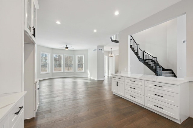 interior space featuring dark wood-type flooring and ceiling fan with notable chandelier