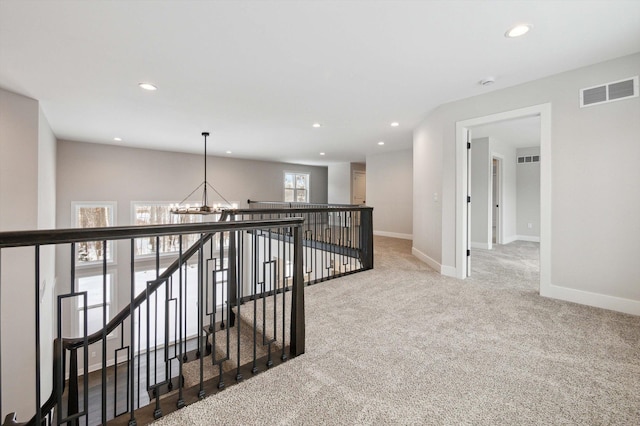 corridor with carpet flooring and an inviting chandelier