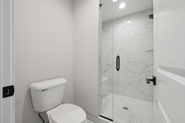 bathroom featuring a shower with shower door and toilet