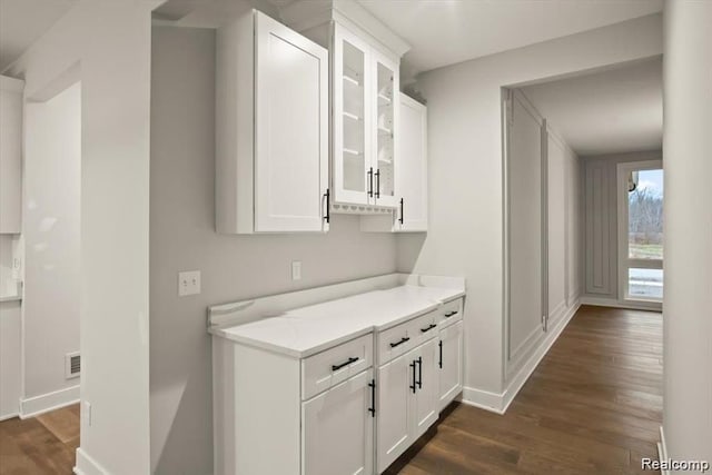 bar featuring white cabinets, dark hardwood / wood-style floors, and light stone counters