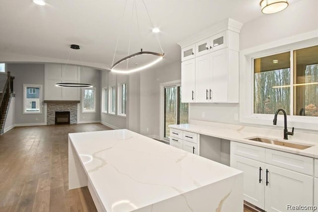 kitchen featuring dark hardwood / wood-style flooring, white cabinetry, hanging light fixtures, and sink