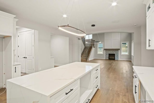 kitchen with a fireplace, a center island, light hardwood / wood-style floors, and white cabinetry