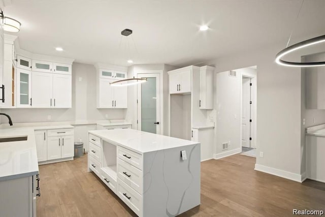 kitchen featuring sink, hardwood / wood-style floors, a center island, white cabinetry, and hanging light fixtures