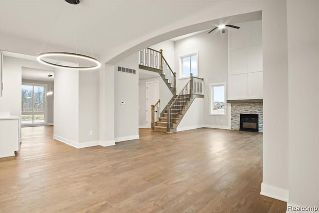 unfurnished living room featuring light wood-type flooring, a fireplace, and a towering ceiling