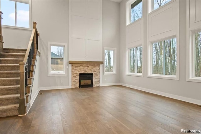 unfurnished living room with a stone fireplace, a healthy amount of sunlight, and wood-type flooring