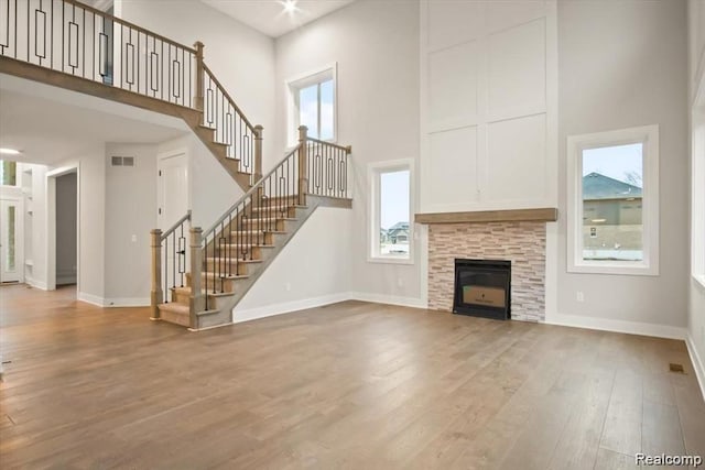 unfurnished living room featuring a fireplace, a towering ceiling, and a healthy amount of sunlight