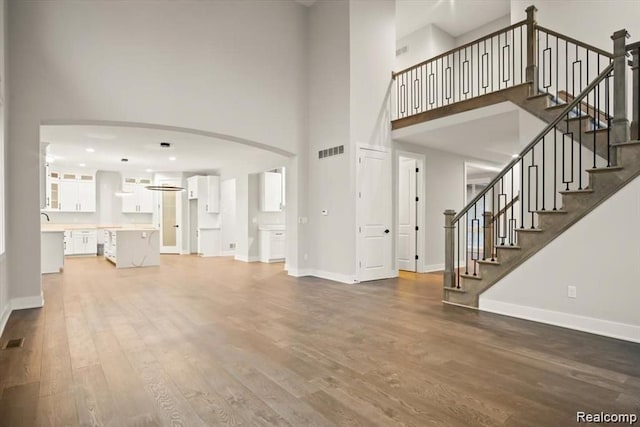 living room with wood-type flooring and a towering ceiling