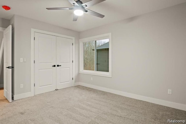 unfurnished bedroom with a closet, light colored carpet, and ceiling fan