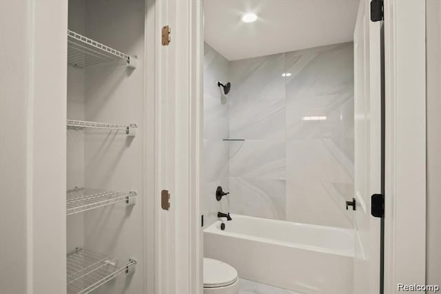 bathroom with tiled shower / bath combo and toilet