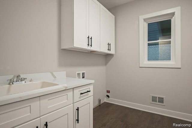 clothes washing area with cabinets, hookup for a washing machine, dark hardwood / wood-style flooring, and sink