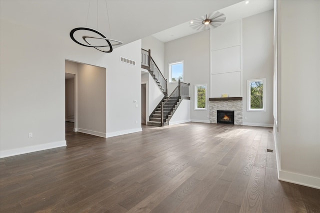 unfurnished living room with baseboards, visible vents, dark wood finished floors, and a towering ceiling