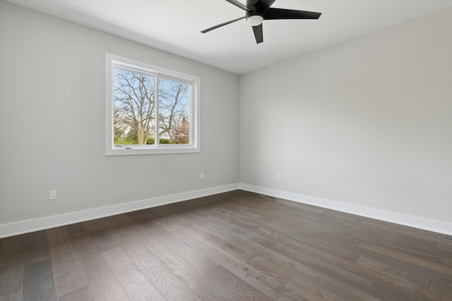 empty room with baseboards, ceiling fan, visible vents, and dark wood-type flooring