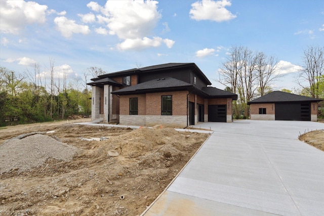 prairie-style home with a garage, concrete driveway, and brick siding