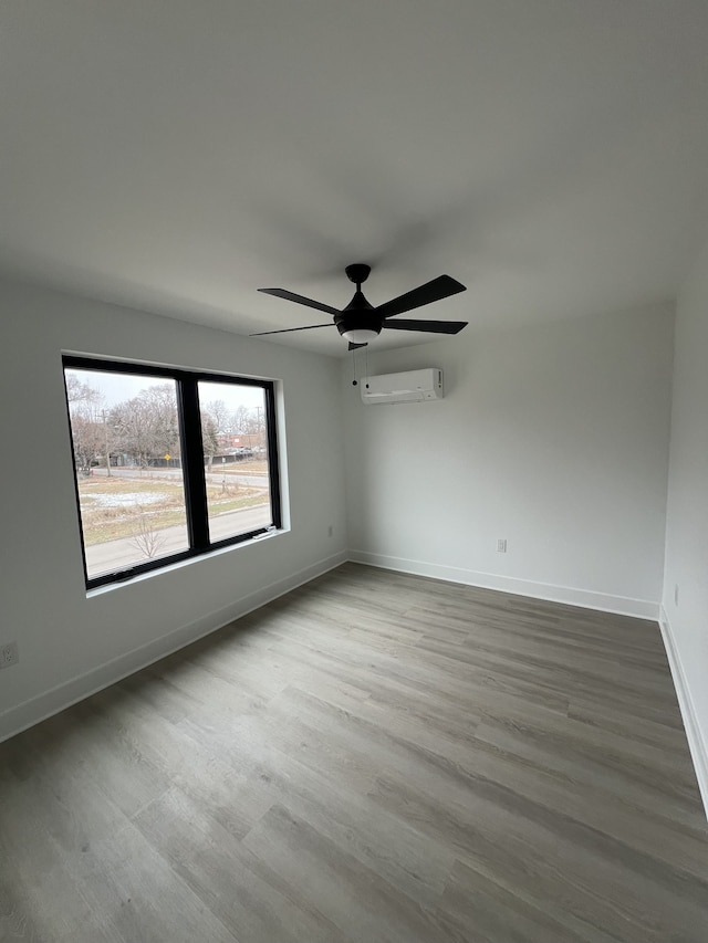 empty room with hardwood / wood-style flooring, a wall mounted AC, and ceiling fan