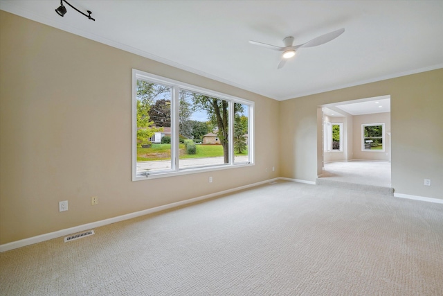 carpeted spare room featuring ceiling fan and crown molding