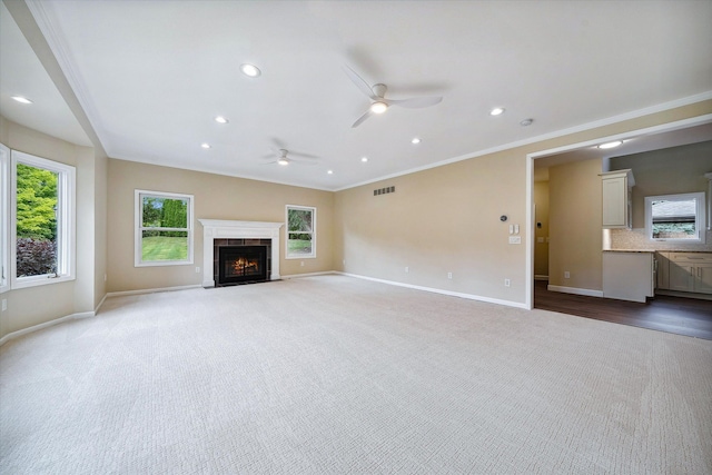 unfurnished living room featuring carpet flooring, ceiling fan, and ornamental molding