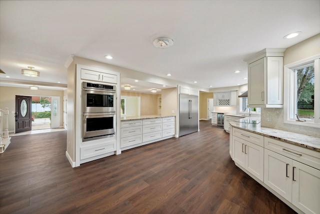 kitchen with backsplash, dark hardwood / wood-style floors, white cabinets, and stainless steel appliances