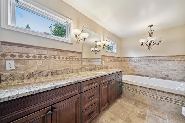 bathroom featuring a chandelier, vanity, a wealth of natural light, and tile walls