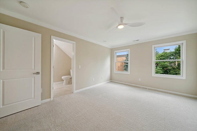 unfurnished bedroom with crown molding, ceiling fan, ensuite bathroom, and light carpet