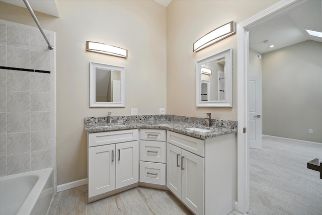 bathroom with vanity, vaulted ceiling, and tiled shower / bath