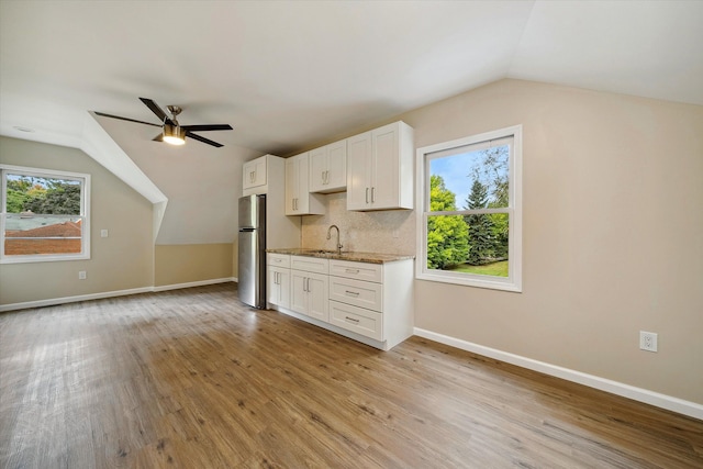 kitchen featuring white cabinets, sink, light hardwood / wood-style flooring, ceiling fan, and stainless steel fridge