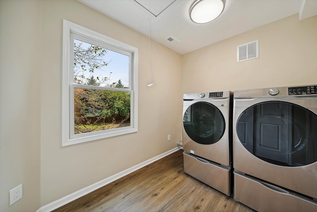 clothes washing area with washing machine and dryer and hardwood / wood-style flooring