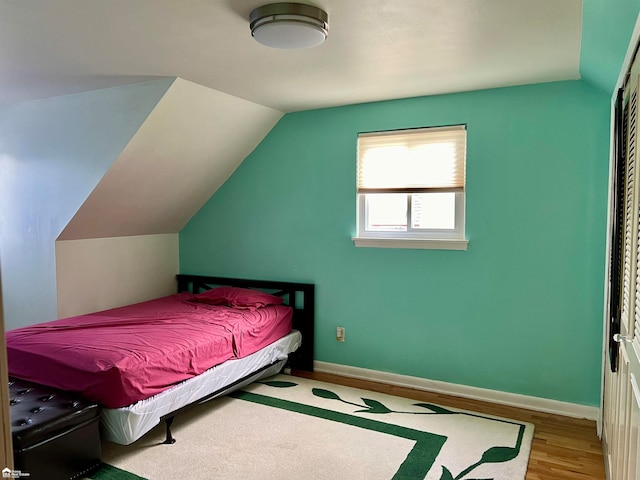 bedroom with light hardwood / wood-style floors and lofted ceiling