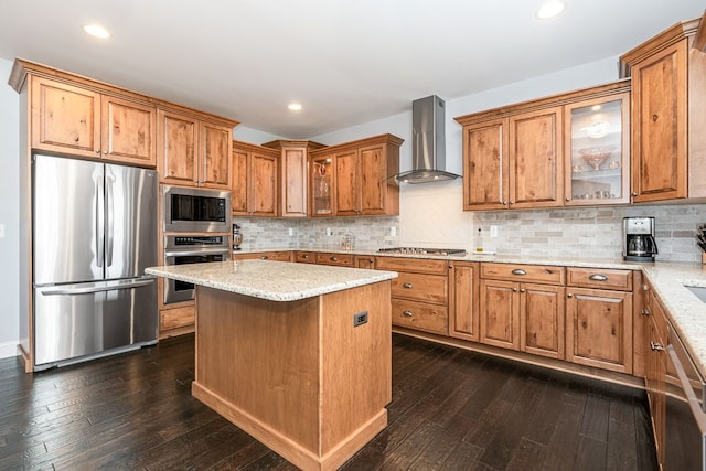 kitchen with stainless steel appliances, a kitchen island, dark wood-type flooring, and wall chimney range hood