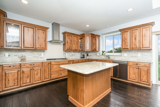 kitchen featuring dark wood-type flooring, sink, appliances with stainless steel finishes, a kitchen island, and wall chimney range hood