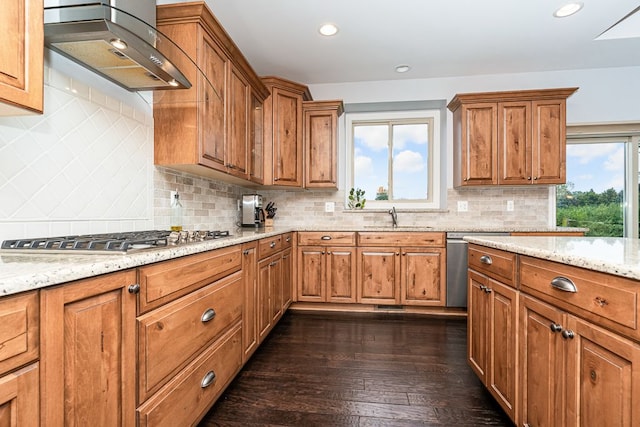 kitchen with stainless steel appliances, range hood, sink, and light stone countertops