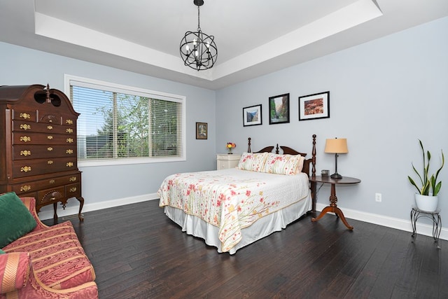 bedroom with dark hardwood / wood-style floors, a notable chandelier, and a tray ceiling