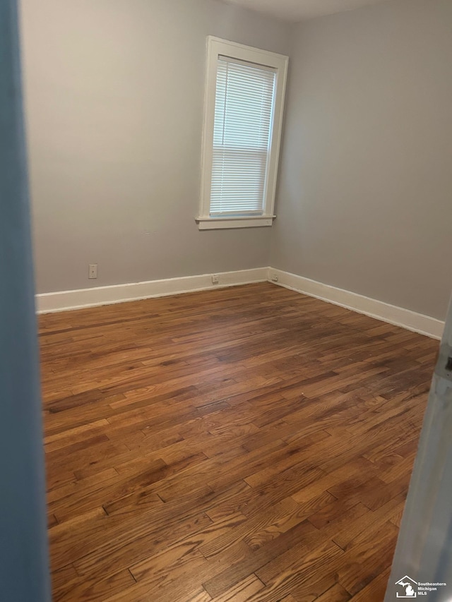 unfurnished room featuring dark wood-style flooring and baseboards